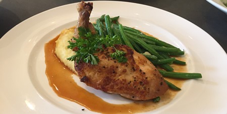 View of Chicken, Potatoes & Green Beans on a White Plate at The Dunes