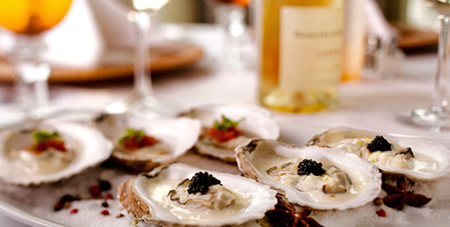 Oysters on a Plate With Glasses of Wine in the Background at The Dunes