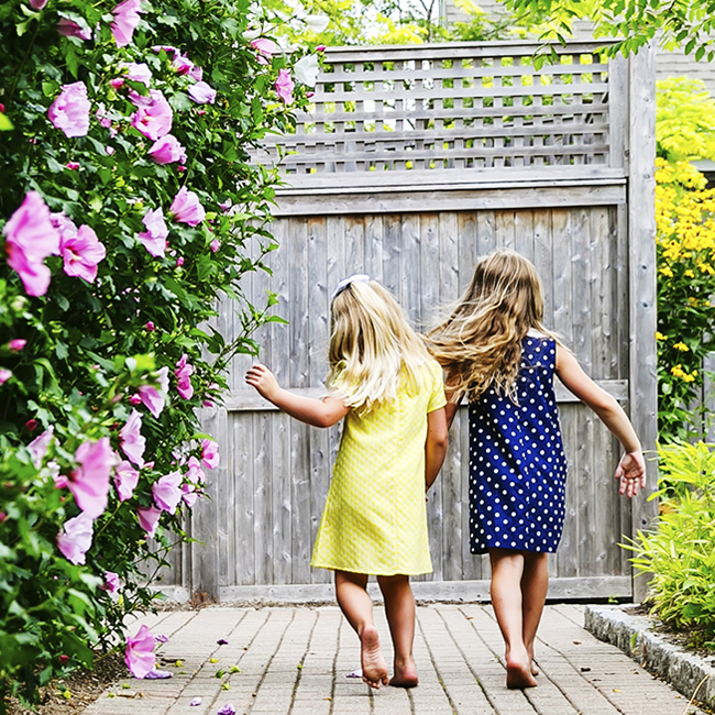 2 young girls holding hands and walking away