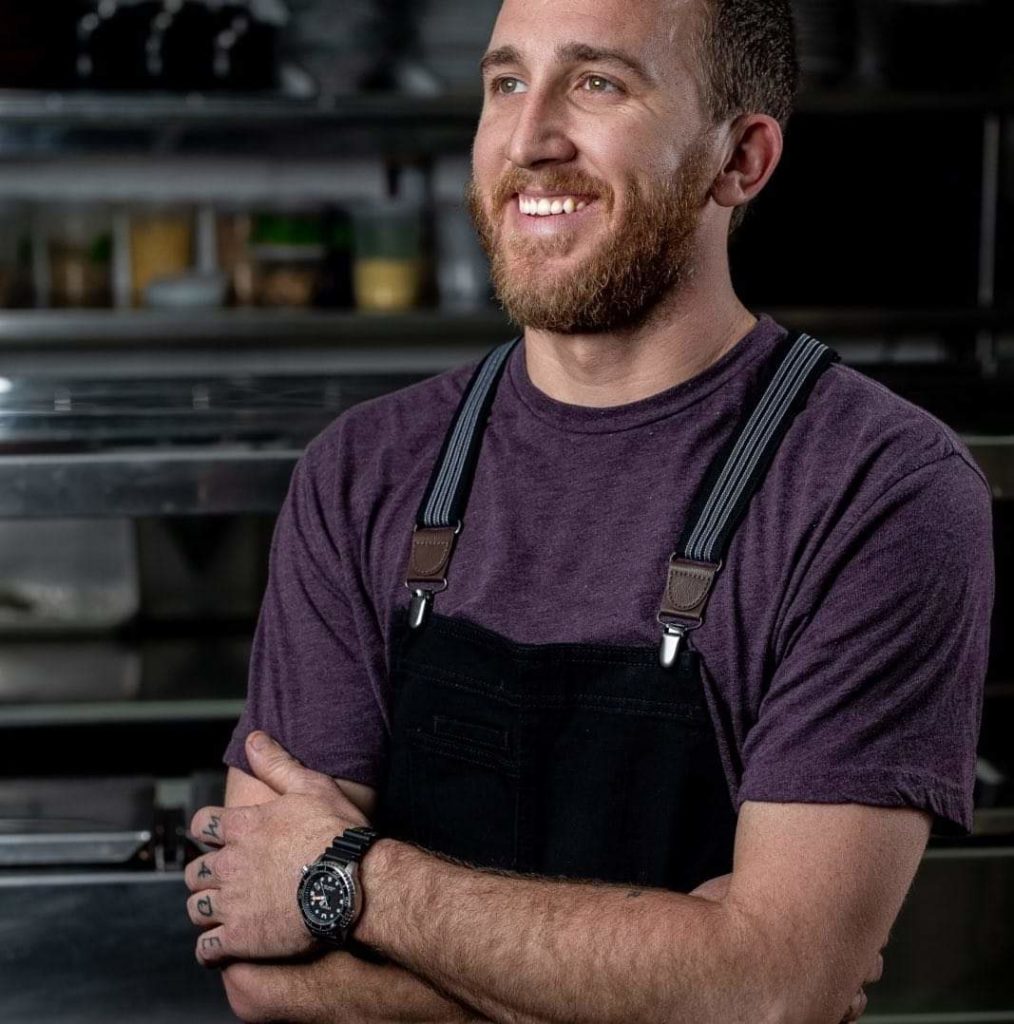 A smiling man with a beard in overalls