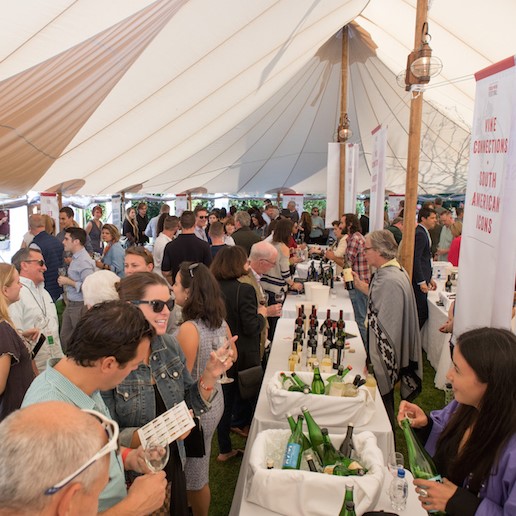 A group of people hanging out under a large event umbrella