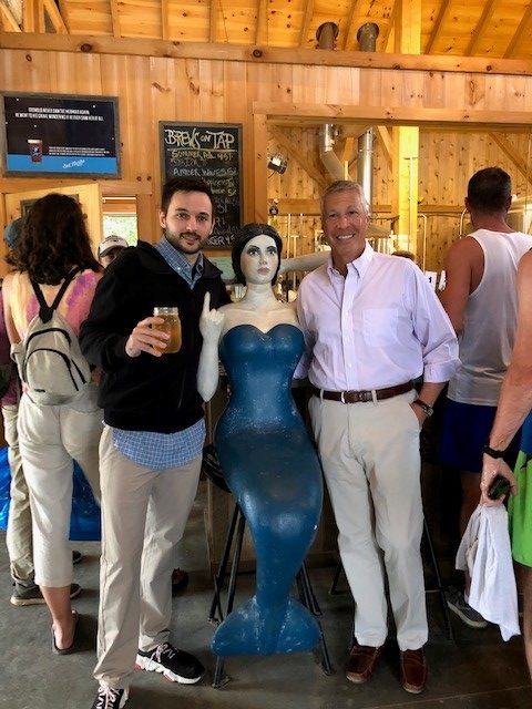 2 men standing with a sculpture of a mermaid in between them