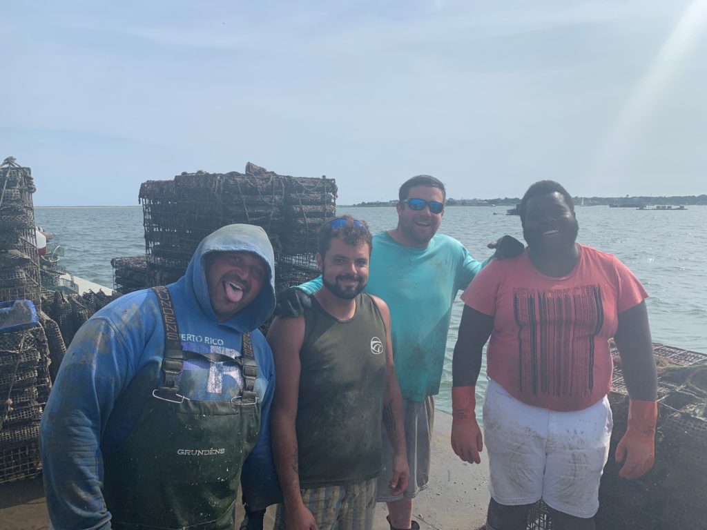 A group of 4 oyster shuckers standing in front of the water