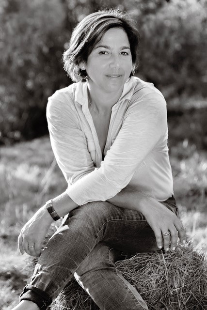 A black and white photo of a woman sitting on hay